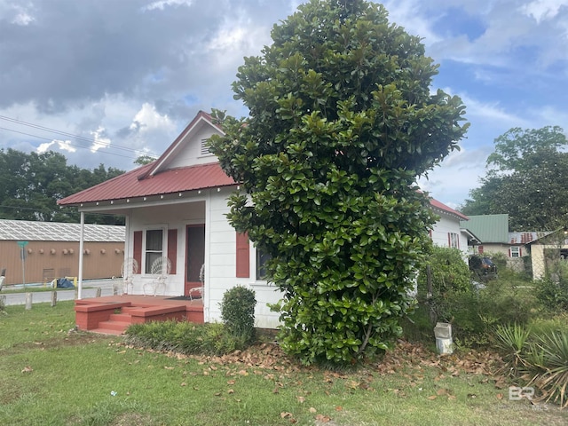 view of side of property featuring a yard, a porch, and metal roof