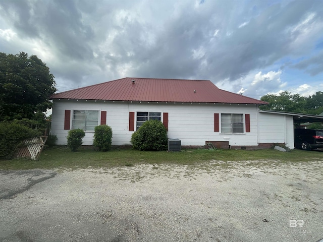 back of property with central AC, metal roof, and a carport