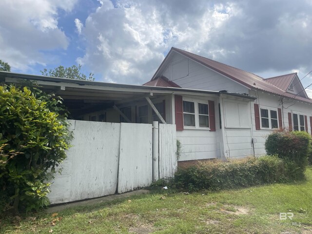view of side of property featuring metal roof and a carport