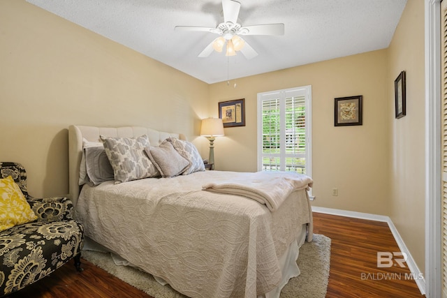 bedroom featuring baseboards, a ceiling fan, dark wood-style flooring, and a textured ceiling