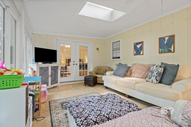 living area featuring light tile patterned floors, a skylight, ornamental molding, and french doors