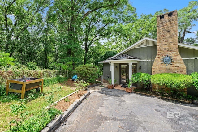 exterior space with a standing seam roof, fence, a chimney, and metal roof
