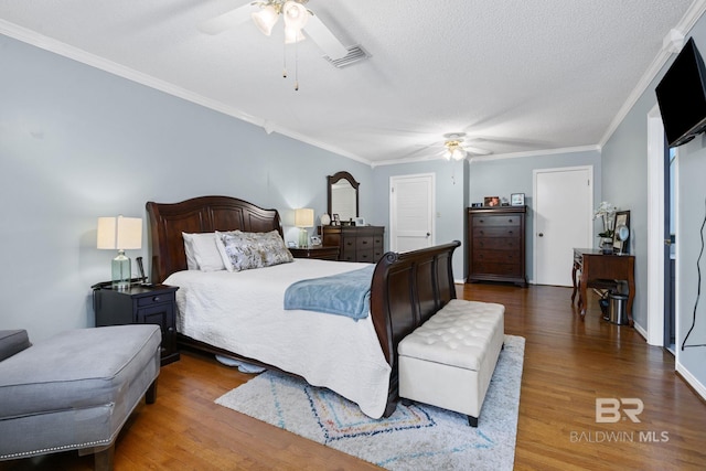 bedroom with visible vents, crown molding, wood finished floors, ceiling fan, and a textured ceiling