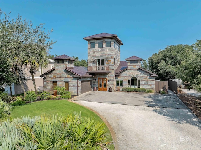 view of front facade featuring a front lawn, driveway, a standing seam roof, stone siding, and metal roof