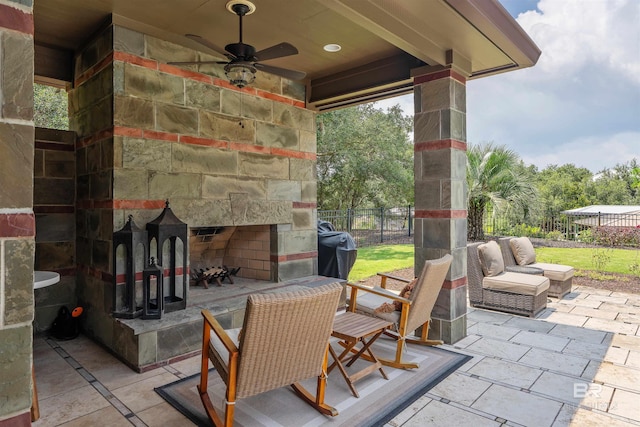 view of patio / terrace with an outdoor living space with a fireplace, fence, and ceiling fan