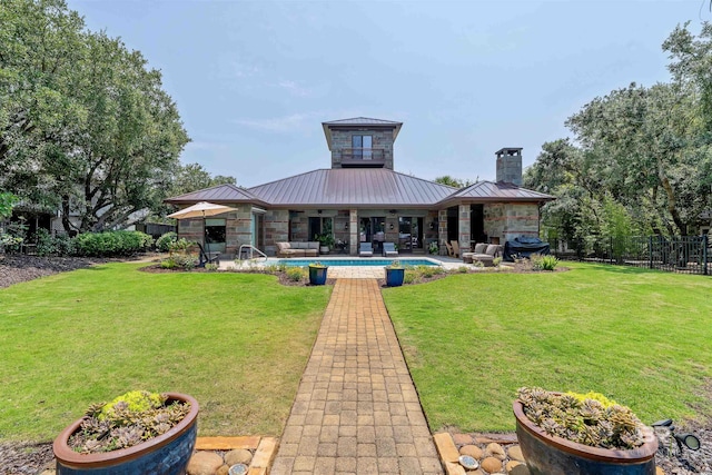 rear view of property featuring fence, a fenced in pool, a standing seam roof, a yard, and metal roof