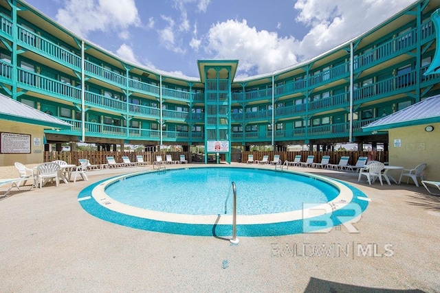 community pool with fence and a patio area