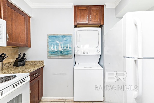 laundry room with stacked washing machine and dryer, crown molding, and baseboards