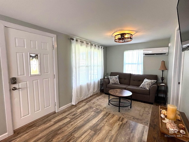 living area featuring baseboards, wood finished floors, and an AC wall unit