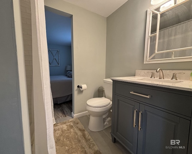 full bath featuring toilet, vanity, and baseboards