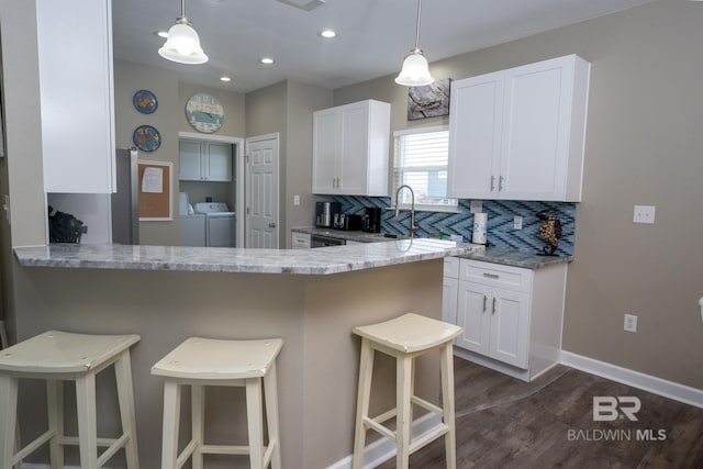 105 Strand Ct, Dauphin Island, AL 36528 - kitchen featuring backsplash, a kitchen breakfast bar, separate washer and dryer, and white cabinetry
