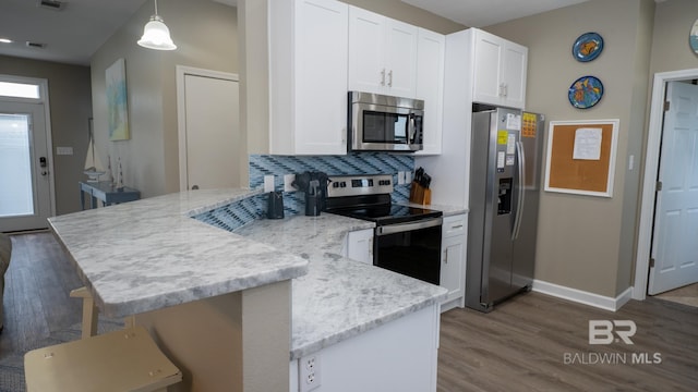 105 Strand Ct, Dauphin Island, AL 36528 - kitchen with dark wood finished floors, a peninsula, white cabinets, and stainless steel appliances