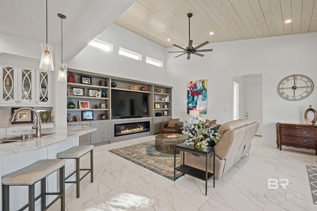 living room with ceiling fan, sink, built in features, high vaulted ceiling, and wood ceiling