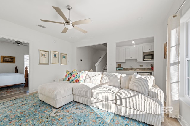 living room with ceiling fan, sink, and light hardwood / wood-style floors