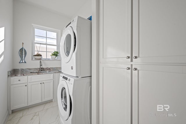 laundry room with stacked washer and dryer, cabinets, and sink