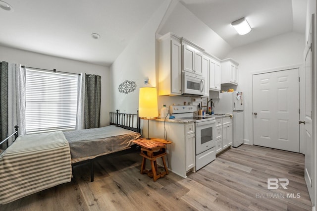 kitchen featuring white appliances, sink, white cabinets, light hardwood / wood-style floors, and lofted ceiling