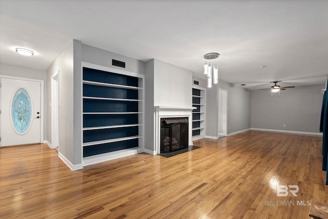 409 E Byron Ave, Mobile, AL 36609 - unfurnished living room with built in shelves, a fireplace with flush hearth, a ceiling fan, and light wood-style floors