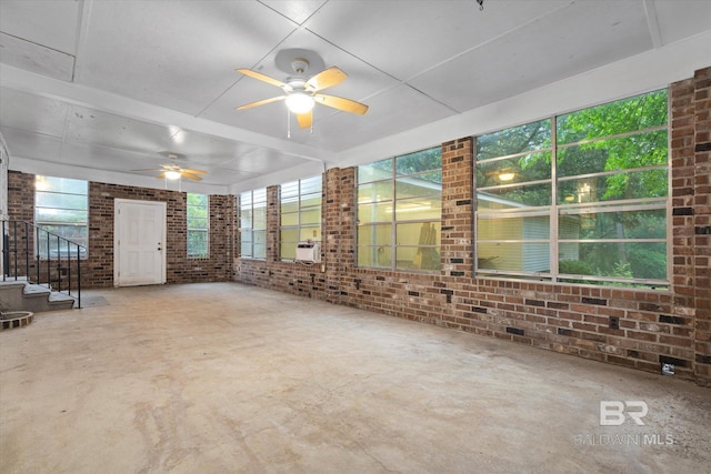 409 E Byron Ave, Mobile, AL 36609 - unfurnished living room featuring brick wall, plenty of natural light, stairs, a ceiling fan, and concrete floors