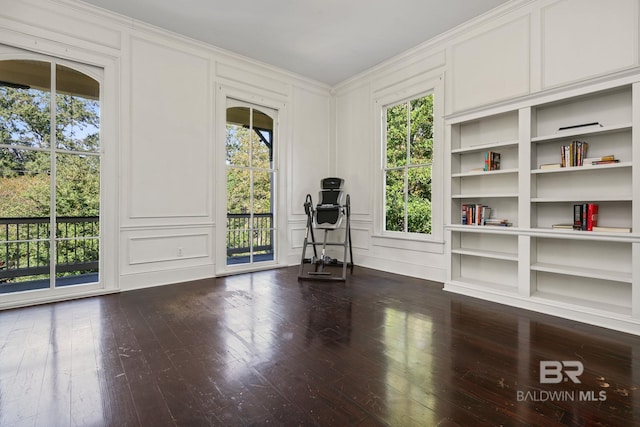 unfurnished room with crown molding, built in features, and hardwood / wood-style floors