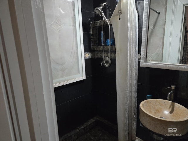 bathroom featuring a tile shower and a sink