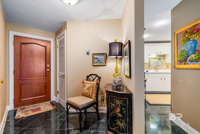 tiled foyer with sink and a textured ceiling