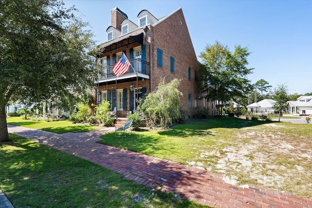 view of front of house with a balcony and a front lawn