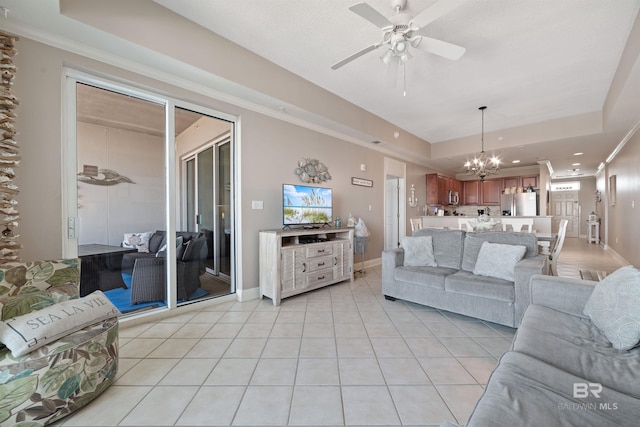 living room with ceiling fan with notable chandelier, a tray ceiling, and light tile patterned floors