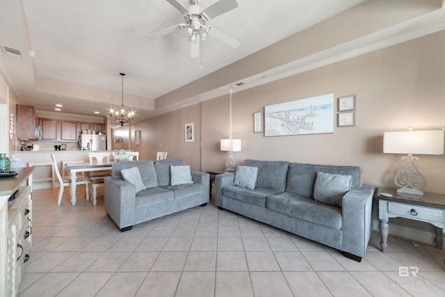 living room with ceiling fan with notable chandelier, light tile patterned flooring, and a textured ceiling