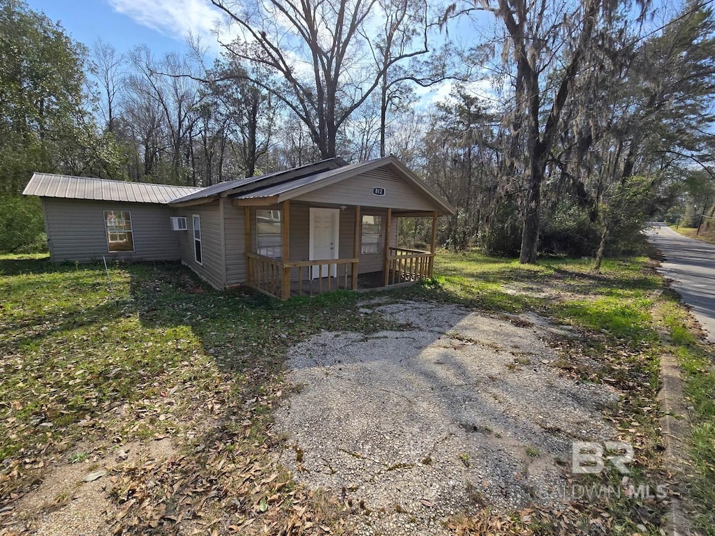 view of front of home with metal roof, a porch, and driveway