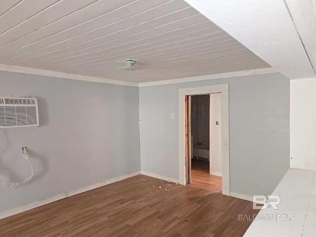 spare room featuring an AC wall unit, wood finished floors, baseboards, and ornamental molding