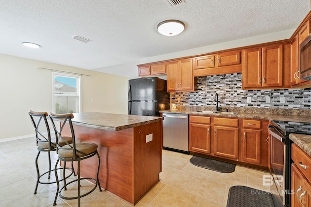 kitchen with appliances with stainless steel finishes, sink, tasteful backsplash, and a kitchen island