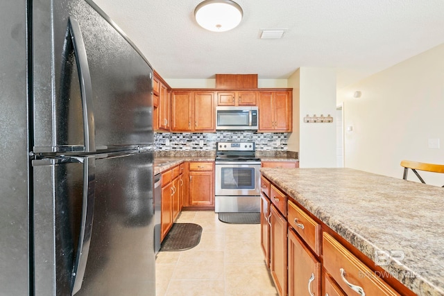 kitchen featuring appliances with stainless steel finishes, light tile patterned floors, and tasteful backsplash