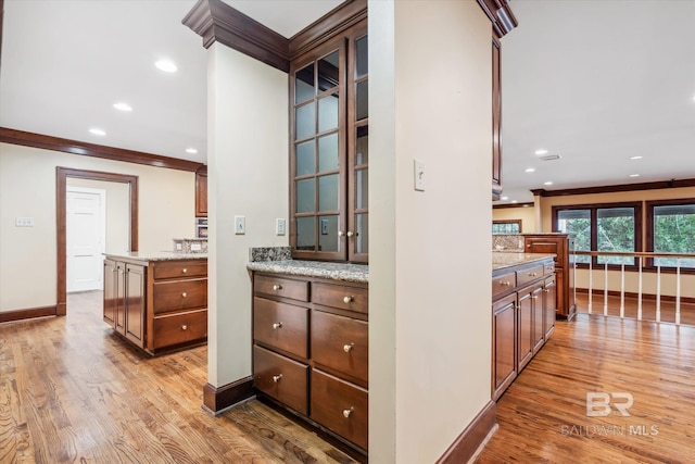 kitchen with light stone countertops, light wood-type flooring, and ornamental molding