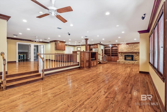 living room featuring hardwood / wood-style flooring, ceiling fan, ornamental molding, and a fireplace