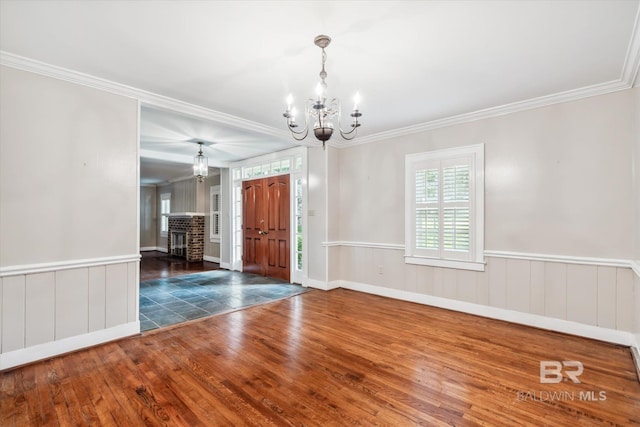 entryway with a brick fireplace, crown molding, dark hardwood / wood-style floors, and a notable chandelier