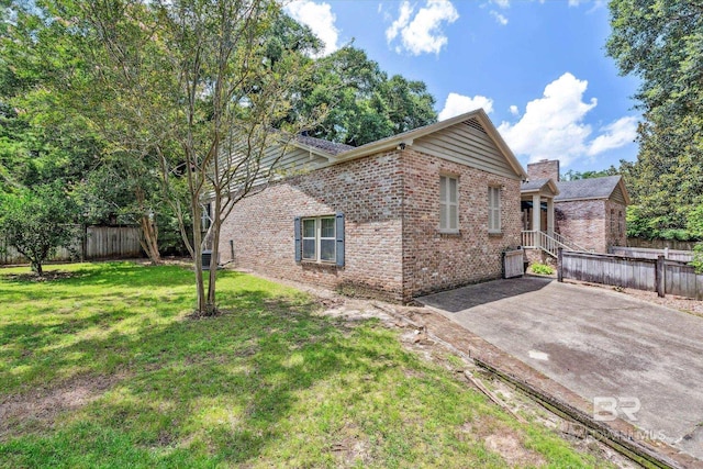 view of side of home featuring a lawn and a patio