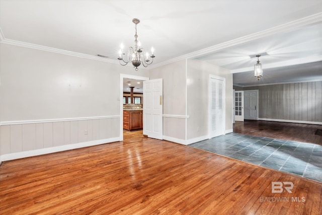 spare room featuring dark hardwood / wood-style floors, an inviting chandelier, and ornamental molding