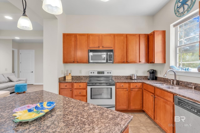 1430 Regency Rd Unit G101, Gulf Shores, AL 36542 - kitchen with stainless steel appliances, hanging light fixtures, dark stone counters, brown cabinetry, and light tile patterned floors