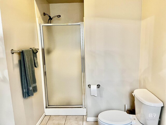 bathroom with tile patterned floors, toilet, and a shower with shower door