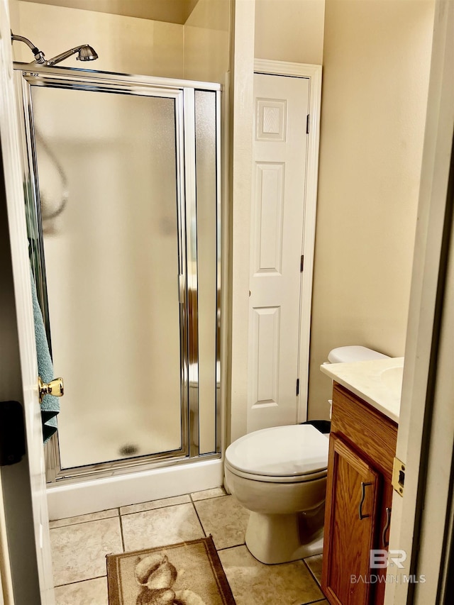 bathroom featuring tile patterned flooring, vanity, toilet, and walk in shower