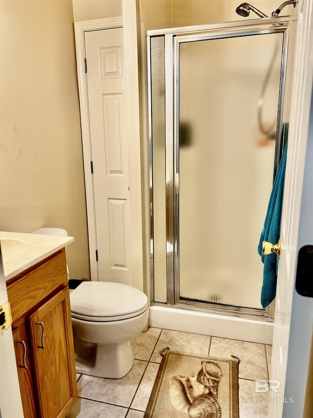 bathroom featuring tile patterned flooring, vanity, toilet, and walk in shower