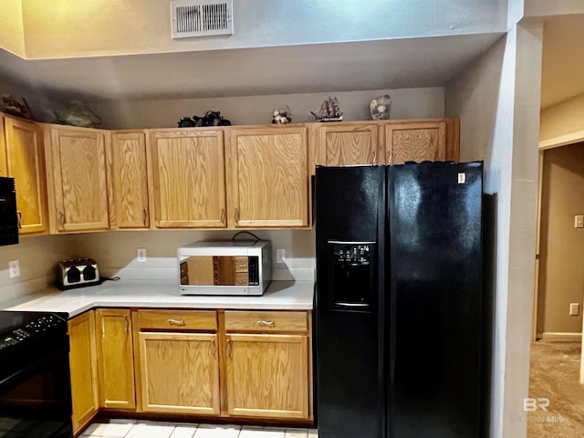 kitchen featuring light tile patterned floors, light brown cabinetry, and black appliances