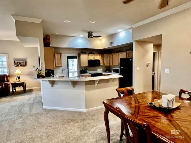 kitchen with light carpet, kitchen peninsula, a breakfast bar, crown molding, and black appliances