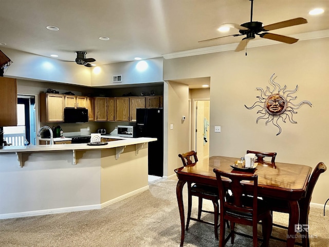 kitchen with black appliances, a kitchen breakfast bar, crown molding, light colored carpet, and kitchen peninsula