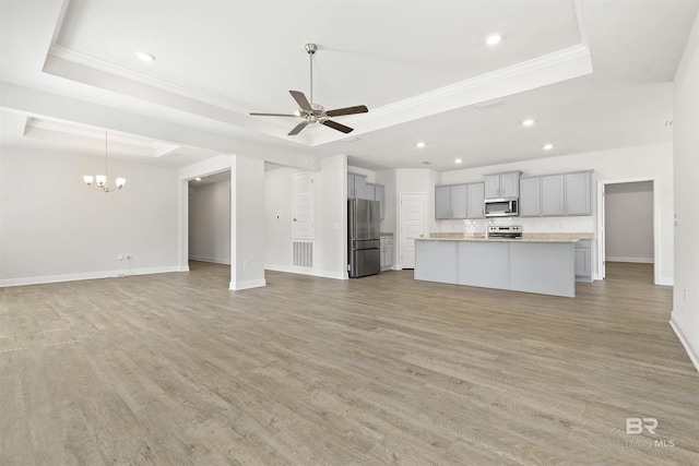 unfurnished living room featuring a raised ceiling, crown molding, light hardwood / wood-style floors, and ceiling fan with notable chandelier