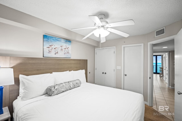 533 W Beach Blvd Unit 602, Gulf Shores, AL 36542 - carpeted bedroom with tile patterned floors, a textured ceiling, multiple closets, ceiling fan, and visible vents
