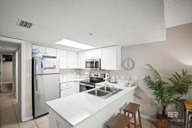 533 W Beach Blvd Unit 602, Gulf Shores, AL 36542 - kitchen with stainless steel appliances, visible vents, light tile patterned floors, a sink, and a peninsula