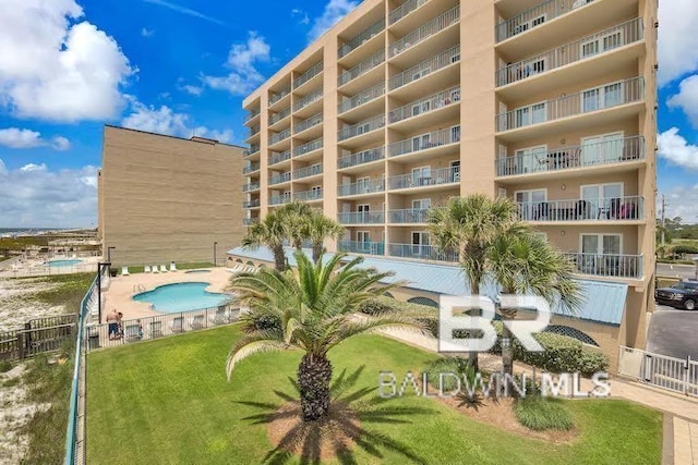 view of building exterior featuring a community pool and fence