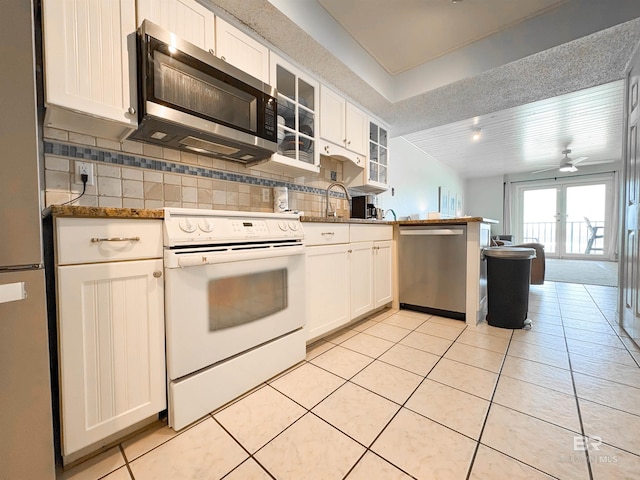 kitchen with tasteful backsplash, light tile patterned flooring, stainless steel appliances, a peninsula, and white cabinetry