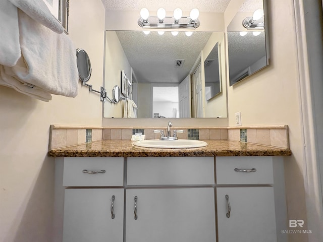 bathroom featuring tasteful backsplash, vanity, a textured ceiling, and visible vents